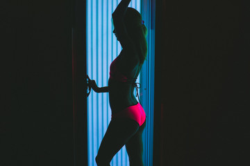 A young girl is sunbathing in a solarium. In a pink swimsuit