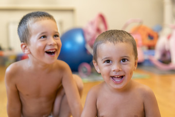 Two brothers laugh, indoor. two cheerful little boys play together, hold hands and scream on white background