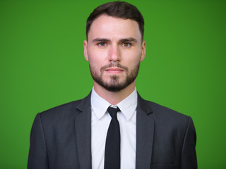 Young handsome bearded businessman against green background