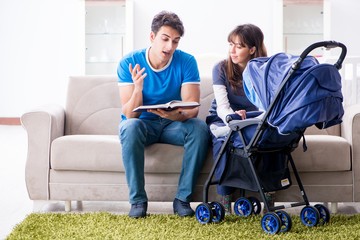 Young parents with their newborn baby in baby pram sitting on th