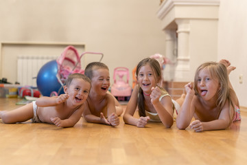 The group of four children lying on the floor. Four happy children lie on the floor. Four brothers and sisters at home in the children's room are playing on the floor