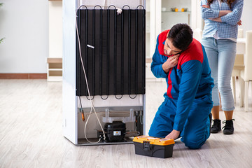 Man repairing fridge with customer