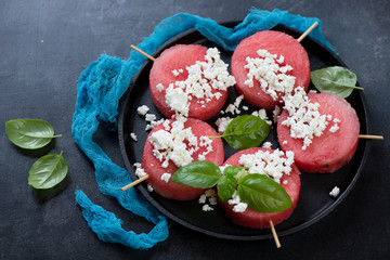 Obraz na płótnie Canvas Wooden skewers with round slices of fresh watermelon and cottage cheese on a metal tray, studio shot