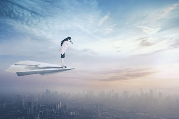 Businesswoman with paper plane and binoculars