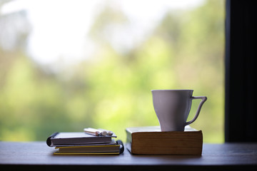 White cup and notebooks at windows