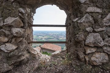 Fototapeta na wymiar Wallpaper background of landscape view from a hole on an antique stone wall in a medieval town. Sermoneta. Italy. No people.