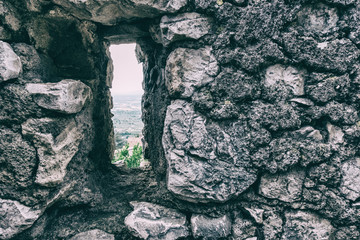 Wallpaper background of landscape view from a hole on an antique stone wall in a medieval town. Sermoneta. Italy. No people.