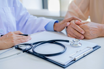 Patient listening intently to a male doctor explaining patient symptoms or asking a question as they discuss paperwork together in a consultation