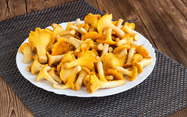 Plate with mushrooms chanterelles on a wooden background, boletus