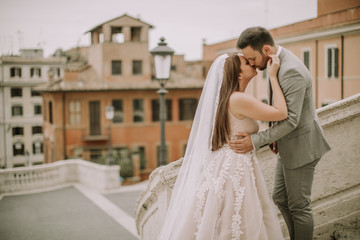 Naklejka premium Young newly married couple posing in Rome with beautiful and ancient architecture in the background