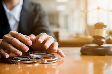Judge gavel, key and handcuffs on table with Justice lawyers having team meeting at law firm. Concepts of law and legal service.