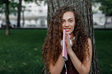 girl student holding book and sitting under tree