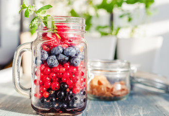 A glass jar with different  fresh summer berries is on the table, a healthy breakfast, a diet, detox, summer treats