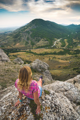 Young woman sits on the edge of the rocky cliff