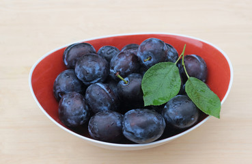 bowl with plums on bright wood