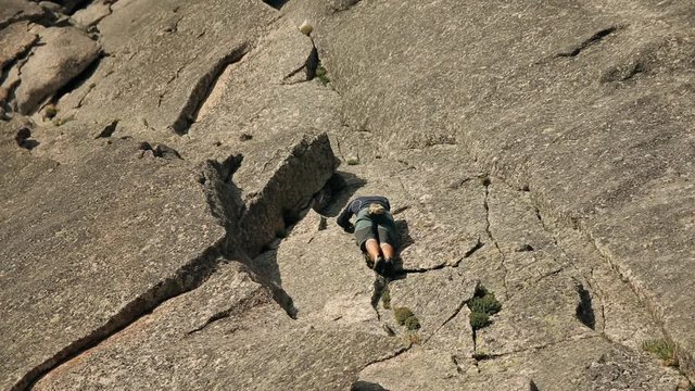 A selfless man climbs to the top of the cliff without a rope.