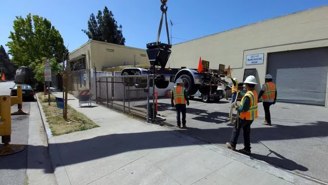 Truck lifted by a construction crane settling on the ground.
