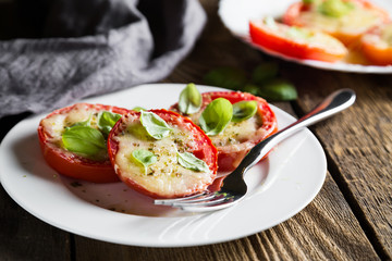 Tomatoes baked under Parmesan with fresh basil