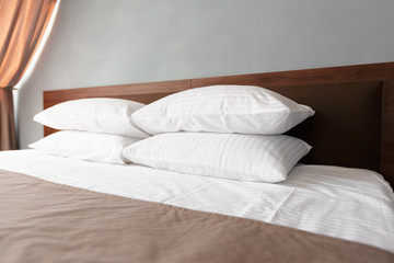 Bed maid-up with clean white pillows and bed sheets in beauty room.