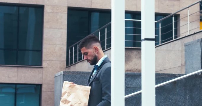 TRACKING Handsome young adult man wearing suit having a meal while walking to work in the morning. 4K UHD 60 FPS SLOW MOTION