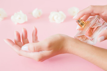 Young, perfect, groomed woman's hands holding a perfume bottle. Care about fresh fragrance of body....