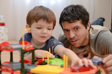 Obraz premium Father and son are playing with toy cars. Happy family playing with toys