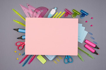 Neon multicolor stationery set and blank pink paper for text on grey background, flat lay.