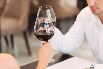 Beautiful young couple with glasses of red wine in luxury restaurant