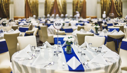 Reception dinner table setup with dinnerware, napkin, spoon, fork and glasses decoration with blue sash cloth stripe
