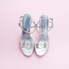 Fashionable women's sandals silver color on a pink background.