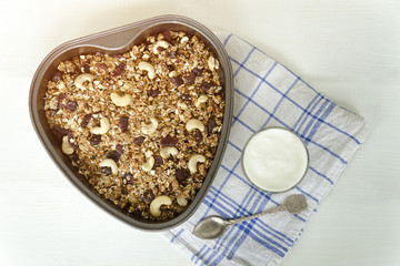 Granola on a baking sheet and yogurt on a light white background.