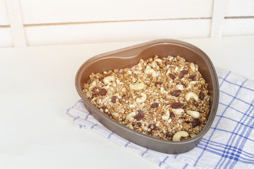 Granola on a  baking sheet heart shaped on a light white background.