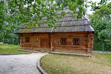 Old ukrtic Ukrinsky house with a wooden roof on the background of the green park zone