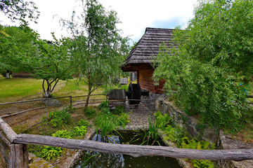 Fototapeta na wymiar A small well with a wheel under the roof of a wooden house