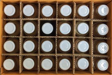 Glass bottles with white bottle caps in a cardboard box, Top view, Packaging concept.