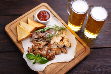 Beer snacks, meat plate. Grilled pork, chicken and beef with hot sauce and and two mugs of lager, appetizing Oktoberfest and pub food