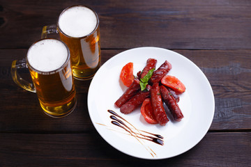 Oktoberfest snacks, popular pub food. Appetizing grilled roasted sausages and two mugs of lager, delicious meals for beer lovers