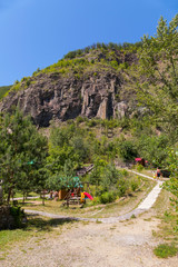 Park area with a playground and other constructions for tourists against the backdrop of a rocky mountain