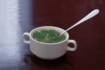 soup with fresh herbs on top in a plate on the table. with the canopy apetically ready for food.