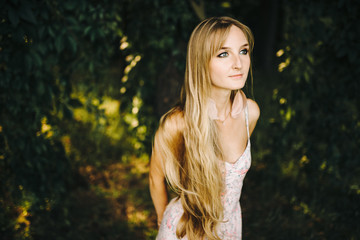 Beauty Girl Outdoors enjoying nature. Beautiful Teenage Model girl with long healthy blowing hair , Sun Light. Glow Sun. Free Happy Woman. Toned in warm colors