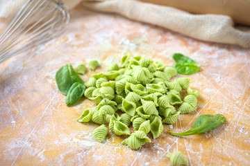 Uncooked homemade green spinach pasta on wooden table, selective focus, copy space