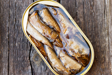 Open tin can of sprats on rustic wooden table