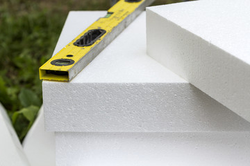 Close-up detail of stack of white rigid polyurethane foam sheets for house insulation and level....