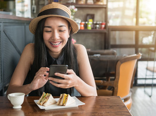 Beautiful woman smiling while using on mobile phone in coffee shop.