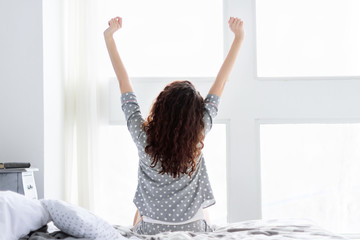 .Young woman girl female adult wearing grey pajamas with white hearts stretching arms in the air...