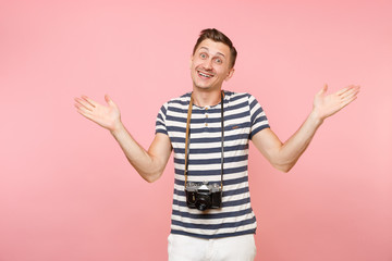 Fototapeta premium Portrait of smiling young photographer man wearing striped t-shirt take pictures on retro vintage photo camera isolated on trending pastel pink background. People sincere emotions lifestyle concept.