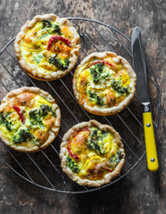 Broccoli cheddar mini savory pies on wooden background, top view. Delicious appetizers, snack,...