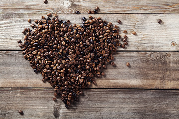Coffee beans in heart shape on wooden background