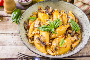 Pasta Conchiglioni with mushrooms in a vintage bowl on concrete background.