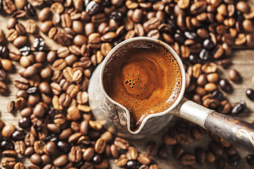 Coffee pot and coffee beans on wooden background